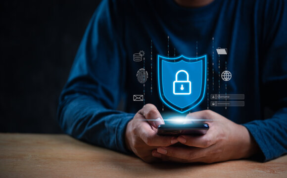 Person holding a smartphone with a digital shield and lock icon. Emphasizes data protection and cybersecurity. Ideal for technology, internet safety, and privacy topics.
