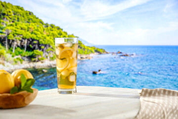 Mocktail drink in a glass on wooden table top with beautiful azure of a sea background. Summer seascape and copy space for products.