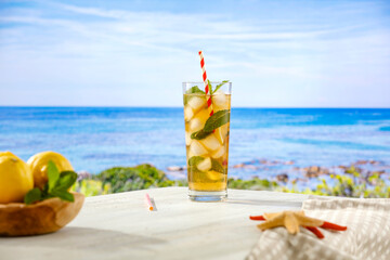 Mocktail drink in a glass on wooden table top with beautiful azure of a sea background. Summer seascape and copy space for products.