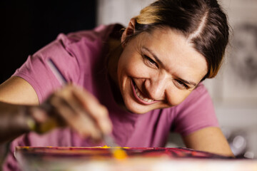 Girl using brush on artistic painting. Female artist creating art.