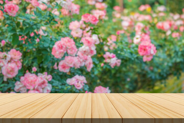 Empty wood table top with blur rose garden background for product display
