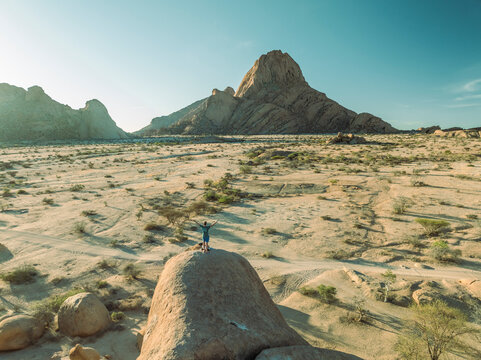 Aerial view of Spitzkoppe Peak and person in rocky Namib desert, Erongo, Namibia. - Powered by Adobe