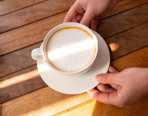 Thai hot tea with foam in white cup on saucer close-up top view