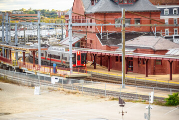 Electric train pulling into a traditional brick train station on a sunny autumn day