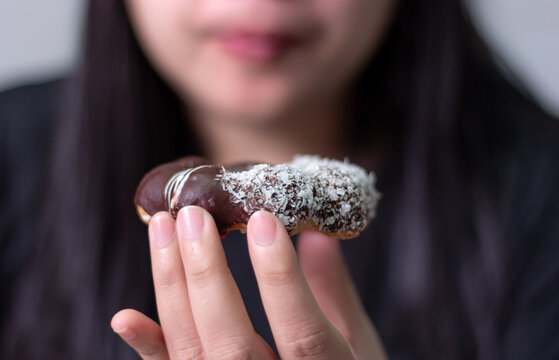 Close up, Woman eating chocolate donu blurred background