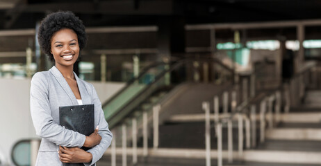Portrait of young female African American job seeker keeping a folder with CV in her hands standing...