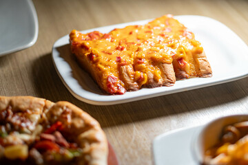 Cheesy bread sticks with melted cheese and tomatoes