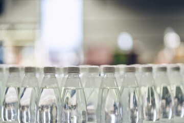 Lots of white caps from drinking water bottles and bottles with clean drinking water on a defocused background. With space to copy. High quality photo