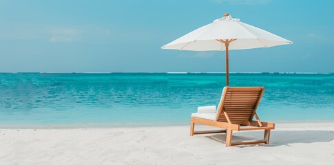 Obraz premium Comfortable chaise lounge with a sun umbrella on a beautiful sandy beach, calm blue sea and sunny skies creating the ideal beach retreat