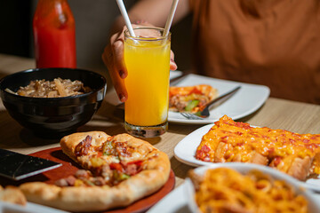 Person dining with pizza, pasta, and orange juice