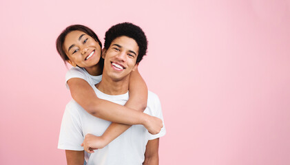 Fototapeta premium Loving girl embracing guy, posing to camera on pink studio background