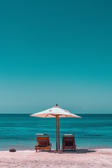 Fototapeta premium Summer concept of umbrellas and wooden deckchairs on a white sandy beach with a view of the blue sea and clear sky.