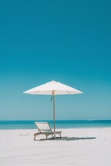 Summer concept of umbrellas and wooden deckchairs on a white sandy beach with a view of the blue sea and clear sky.