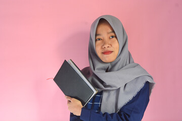 Portrait of Asian woman reading a book on isolated pink background