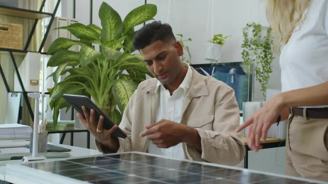 Medium shot of diverse coworkers sharing ideas on solar panel implementation when discussing business at office