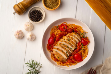 Grilled chicken breast with spaghetti tomato sauce in white plate.Top view