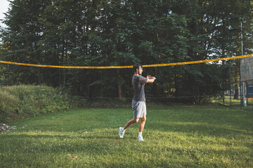 Black-haired badminton player practices his strokes on the grass court. Individual technique training. Amateur concept of the sport. The joy of the game