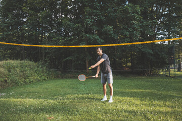 Black-haired badminton player practices his strokes on the grass court. Individual technique training. Amateur concept of the sport. The joy of the game