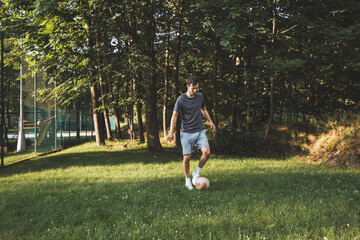 Black-haired athlete plays a friendly football match on the lawn. Amateur sport. Man playing with a ball. Dribbling practice. Sport lifestyle