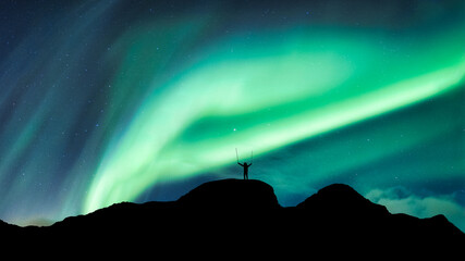 Aurora borealis with starry glowing over hiker standing on summit mountain in the night © Mumemories
