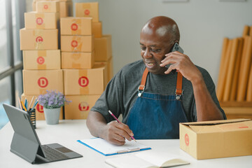 Business owner on phone, packing boxes, taking notes, working on laptop. Small business operations,...