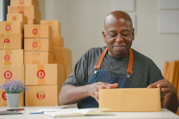 Man in apron packing boxes at a table, surrounded by boxes. Business, shipping, e-commerce, and delivery concept.