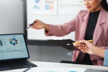 Businesswomen discussing financial charts and graphs on laptop and clipboard during meeting © amnaj