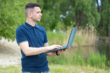 Young man works on a laptop while outdoors. Working outdoors is the best alternative to the office....