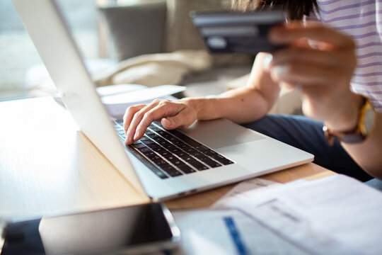Close up of a woman holding credit card and typing on laptop