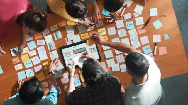 Aerial view of developer team discussing and showing digital program and writing by using Ux Ui design. Top down view of business people develop wireframe prototype for phone and computer. Symposium.
