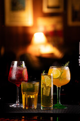 set of drinks of various sizes and refreshing and tropical colors on a blurred bar background