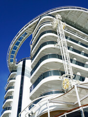 High back of a large cruise ship with balconies on a blue sky background, ship hull washing facility