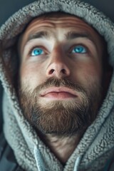 A person with blue eyes and a hoodie, potentially anonymous or mysterious
