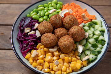 Healthy buddha bowl with falafel and vegetables on plate. 