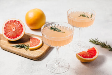 Elegant grapefruit and rosemary cocktails served in crystal glasses with fresh grapefruit slices, set against a light background. Perfect for summer gatherings and holiday party. Refreshing mocktail.