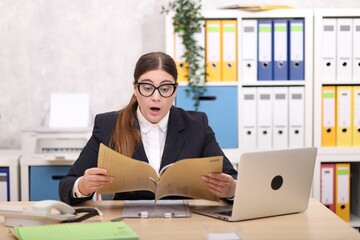 Sekretärin im schwarzen Business Anzug sitzt am Schreibtisch und ist erstaunt über eine Akte