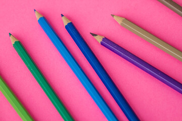 Dynamic display of colorful pencils on a contrasting pink backdrop.