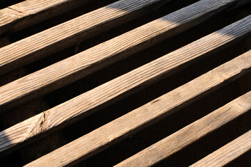 Background of wooden slats diagonally outdoors in daytime sunlight
