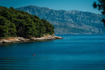 Obraz premium Beautiful view of the sea with someone swimming in it and mountains from the island Brac in Croatia while traveling in Europe.