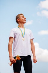 A young athlete is victorious, holding a gold medal and trophy against a backdrop of a blue sky