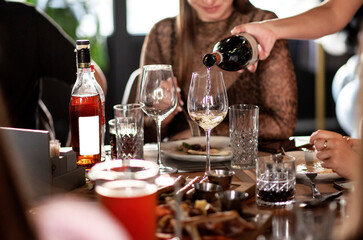 Hand pours wine from a glass bottle into a glass