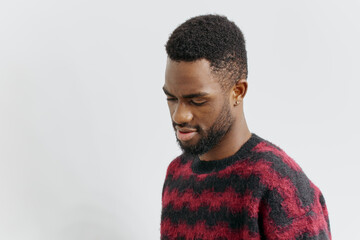 Obraz premium Confident young african american man in stylish red and black sweater posing against a neutral background