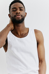 Young man in white tank top holding head in distress, expressing stress or headache in minimalist setting