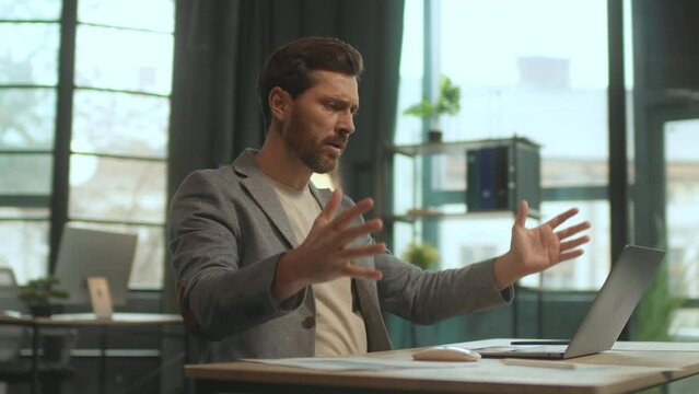 Tracking moving around 360 degree shot of stressed young man working on laptop in office. Footage of emotional handsome business man sitting at desk. Angry guy at work. Failure