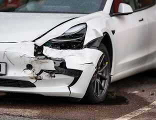 Crashed white electric car waiting for repair.