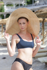 Young woman on beach wearing bikini and wide brim straw hat