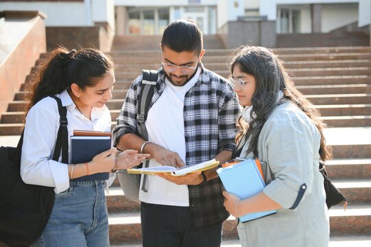 Three international students standing and holding a books