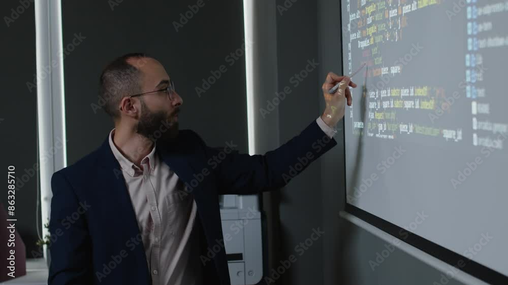 Wall mural medium side shot of young nerdy male programming teacher circling code variables on projector screen