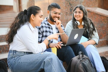 group of young students checking exam results or waiting for project approval on laptop at collage campus