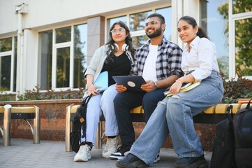 group of young students checking exam results or waiting for project approval on laptop at collage campus